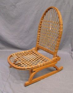 a wooden rocking chair with woven seat and backrest, on a gray background in front of a white backdrop