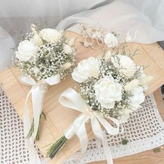 two bouquets of white flowers sit on a cutting board