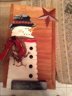 a snowman made out of toilet rolls sitting on top of a wooden box with a star