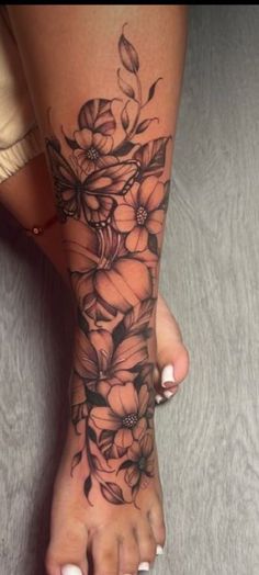 a woman's foot with flowers and leaves on the bottom part of her leg