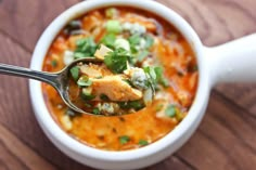 a spoon full of soup on top of a wooden table