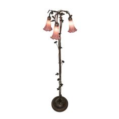 a lamp that is on top of a pole with three flowers hanging from the base