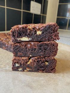 three brownies stacked on top of each other in front of a tiled countertop