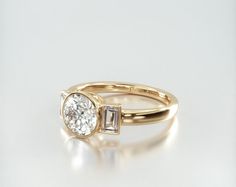 a gold ring with a diamond on the side and a baguette stone in the middle