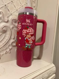 a pink tumbler cup sitting on top of a white mantle next to a wall