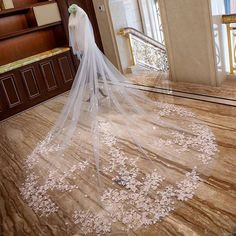 the bride is wearing a wedding veil with flowers on it and she is walking down the stairs