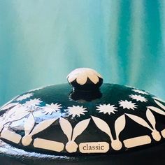 a black cake with white flowers on it sitting on a blue tableclothed surface