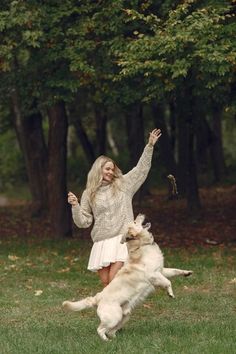 a woman is playing with her dog in the park