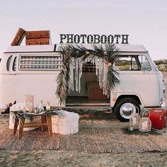 an old vw camper parked on the beach with a sign above it that says photo booth