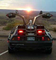 the back end of a car parked in a parking lot with the sun setting behind it