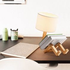 a lamp sitting on top of a wooden table next to a book and an open book