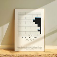 a white framed poster with the words pink floyd on it in front of a wall