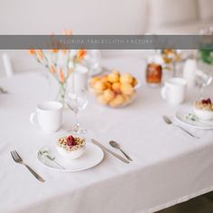 a white table topped with plates and cups filled with food