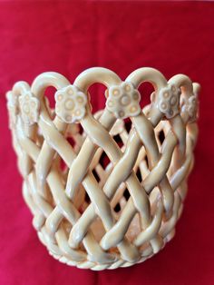 a close up of a decorative basket on a red surface with white flowers in the center