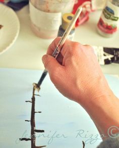 a person holding a paintbrush in their hand and painting a boat on the water