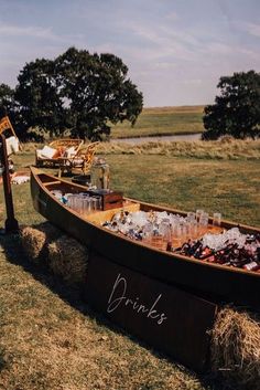 a boat filled with drinks sitting on top of a lush green field