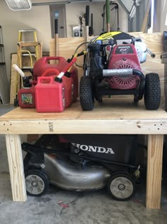 a lawn mower sitting on top of a wooden table next to other tools and equipment