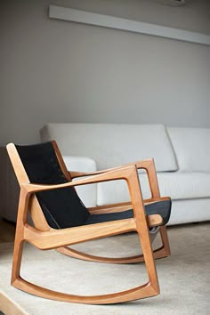 a wooden rocking chair sitting on top of a carpeted floor next to a white couch