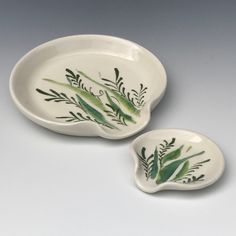 two white dishes with green leaves painted on them