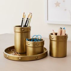 three metal containers with pens and pencils in them