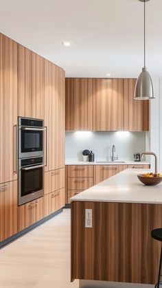 a modern kitchen with wooden cabinets and an island in the middle, along with a bowl of fruit on the counter