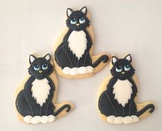 three decorated cookies with black and white cats on them