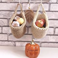 two baskets hanging from hooks on a brick wall next to an orange pumpkin with shells in it