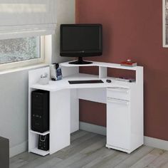 a computer desk with a monitor, keyboard and mouse on it in front of a red wall