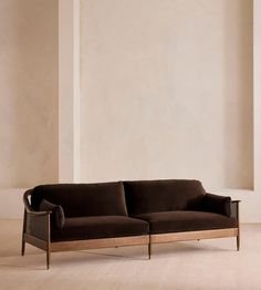 a couch sitting on top of a hard wood floor next to a white wall in an empty room