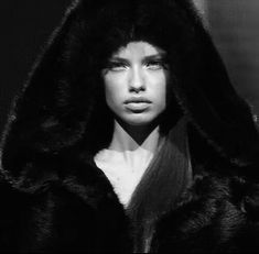 a woman with long hair wearing a black hooded jacket and fur coat over her head