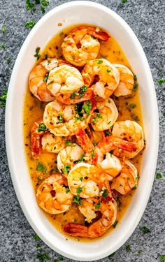 a white bowl filled with cooked shrimp and garnished with parsley on top