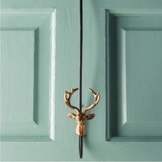 a deer head mounted to the side of a green door with two hooks on it