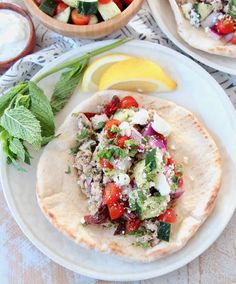 two pita breads on a plate with vegetables and yogurt