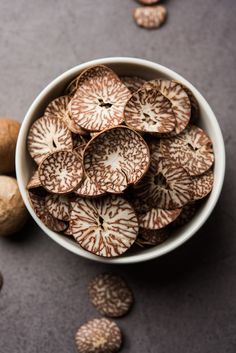 a white bowl filled with nuts on top of a gray counter next to other nuts