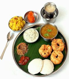 an assortment of food items on a plate with silver spoons and bowls around it