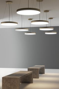 several circular lights hang from the ceiling above concrete benches