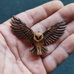 a small owl figurine sitting on top of a persons palm in a hand