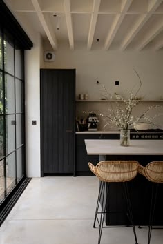 a kitchen with two stools next to a counter top and an open door leading outside