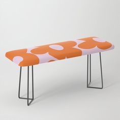 an orange and white polka dot bench with metal legs on a gray background in the shape of a flower