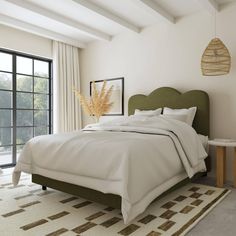 a bedroom with a bed, rug and large windows