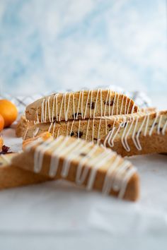 two pieces of bread with icing on them and some oranges in the background