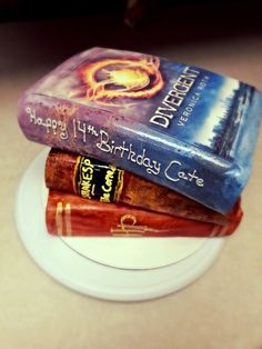 three books stacked on top of each other in front of a white plate with gold trim