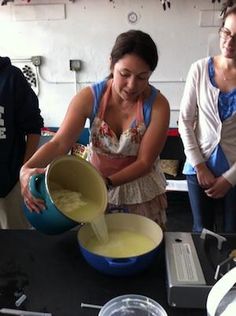 some people are standing around mixing something in a bowl and another person is looking at the camera