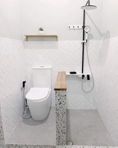 a white toilet sitting in a bathroom next to a shower head mounted on a wall