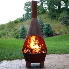 a fire pit sitting on top of a stone patio next to a lush green field