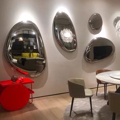 a room filled with furniture and mirrors on the wall above it is a round table surrounded by chairs