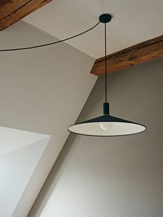 a light fixture hanging from the ceiling in a room with white walls and wooden beams