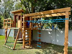 a wooden play set in the backyard with climbing bars and ladders attached to it