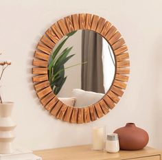 a mirror that is on the side of a table next to a vase and potted plant