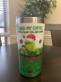 the grinch is wearing a santa hat and holding a cup with coffee on it